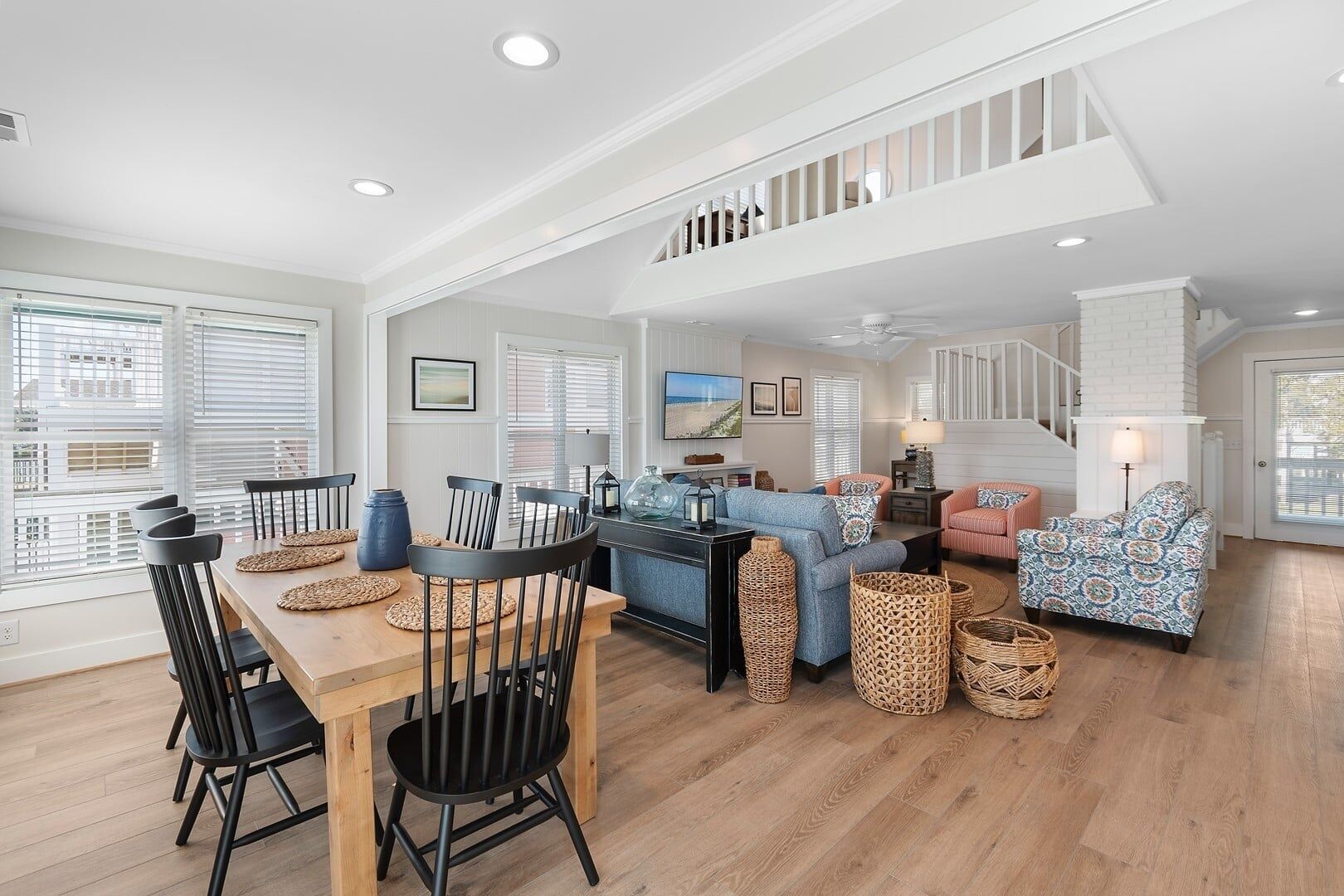 A spacious living area with a dining table, chairs, sofas, and a staircase.