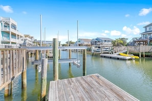 A wooden dock extending into calm water with boats docked nearby, surrounded by residential buildings.