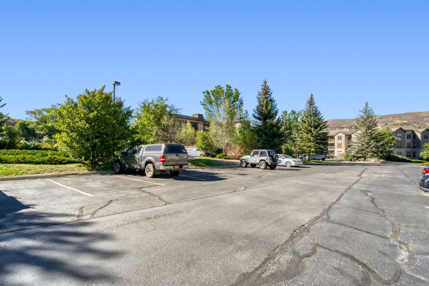 A parking lot with several vehicles, including SUVs and a compact car.