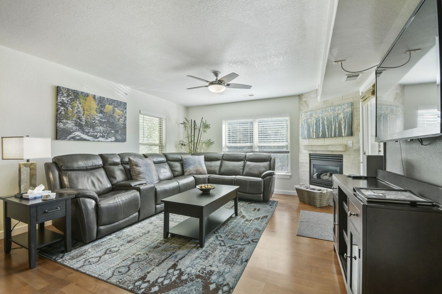 A living room with a sectional sofa, a coffee table, a TV, and a fireplace.