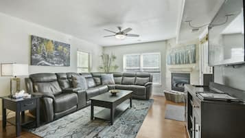 A living room with a sectional sofa, a coffee table, a TV, and a fireplace.