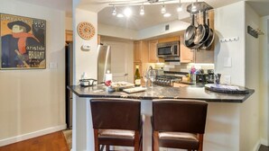 A modern kitchen with a central island, stainless steel appliances, and hanging pots. - River Pines C207 2 Bedroom Condo by RedAwning (Edwards)