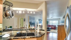 A kitchen with a large island, stainless steel appliances, and a dining area with a sofa and table. - River Pines C207 2 Bedroom Condo by RedAwning (Edwards)