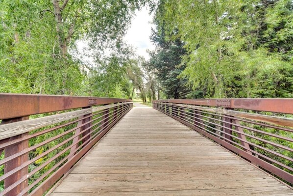 A wooden pedestrian bridge with metal railings, surrounded by dense green foliage. - River Pines C207 2 Bedroom Condo by RedAwning (Edwards)