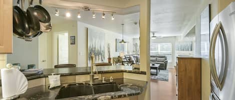 A kitchen with a black countertop, stainless steel appliances, and a large window.