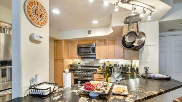 A modern kitchen with a marble countertop, stainless steel appliances, and wooden cabinets. - River Pines C207 2 Bedroom Condo by RedAwning (Edwards)