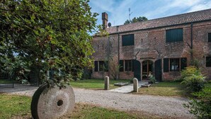 Un bâtiment en briques avec un chemin de gravier, une grande sculpture en pierre et un arbre.