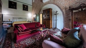 Une pièce avec un canapé en velours rouge, un meuble en bois et un tapis à motifs.