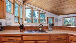 A kitchen with large windows, wooden cabinets, and a stove. - MCNA33 - Spacious Home with Great Views, AC, Hot Tub (Sunriver)