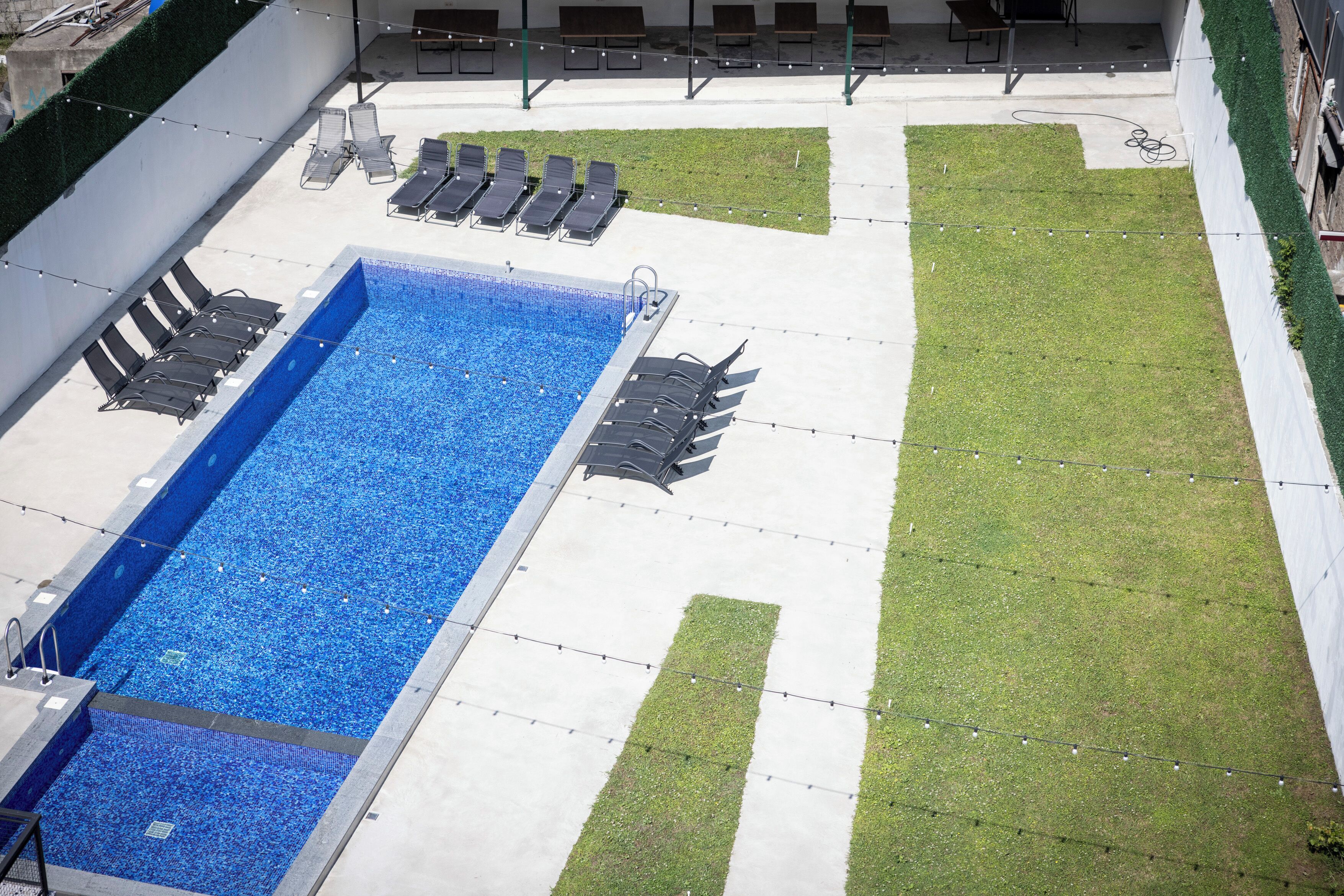 A rooftop pool with lounge chairs and a grassy area.