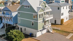 A multi-story building with a balcony on the second floor, a covered porch on the ground floor, and a view of the ocean. - Shore Sounds Fun | Beach Views + Pet Friendly! (Surf City)