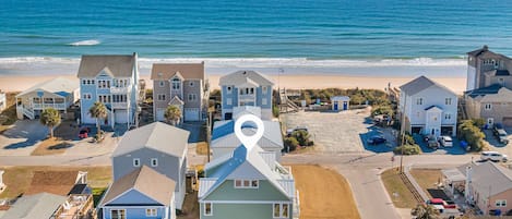 Un quartier résidentiel situé sur la côte, avec des maisons, une plage et une vue dégagée sur l’océan.