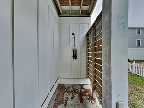 A narrow, enclosed porch with a wooden ceiling and a white door.