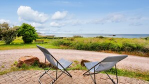 Twee opklapbare stoelen langs een geplaveid pad, met uitzicht op een grasveld en een waterpartij in de verte.