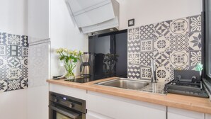 A modern kitchen with patterned tiles, a stainless steel sink, a coffee maker, and a built-in oven.