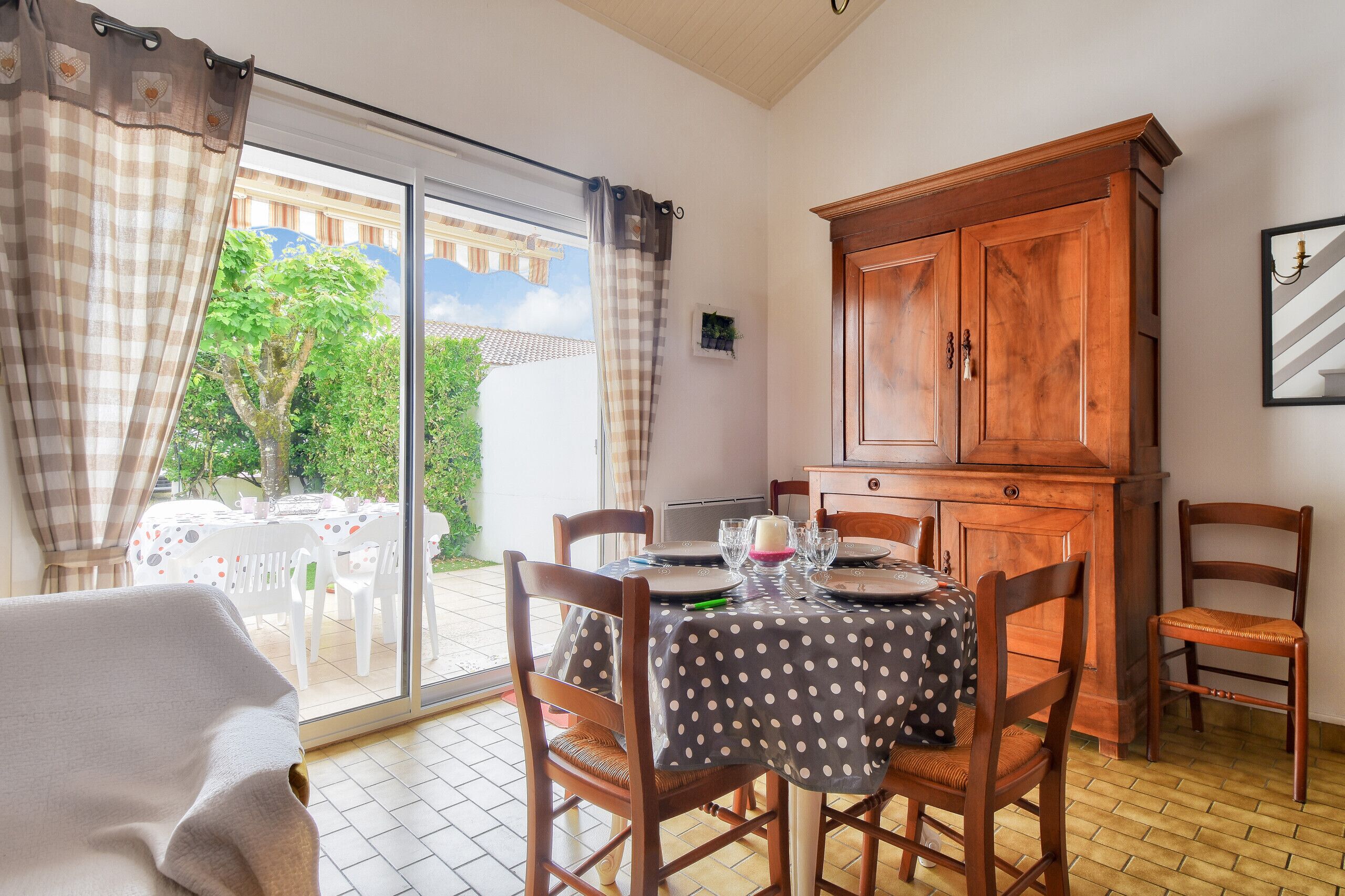 Un coin repas avec une table dressée pour quatre personnes, des chaises en bois et un buffet.