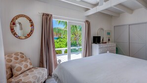 Ein Schlafzimmer mit einem Bett, einem Schminktisch, einem Fernseher und einem großen Fenster mit Vorhängen.
