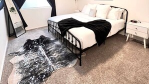A bedroom with a bed, bedside table, nightstand, and a hanging plant. - Modern & Stylish, King bed, WiFi (Spokane Valley)