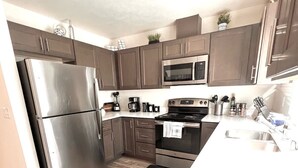 A modern kitchen with stainless steel appliances, wooden flooring, and a granite countertop. - Modern & Stylish, King bed, WiFi (Spokane Valley)