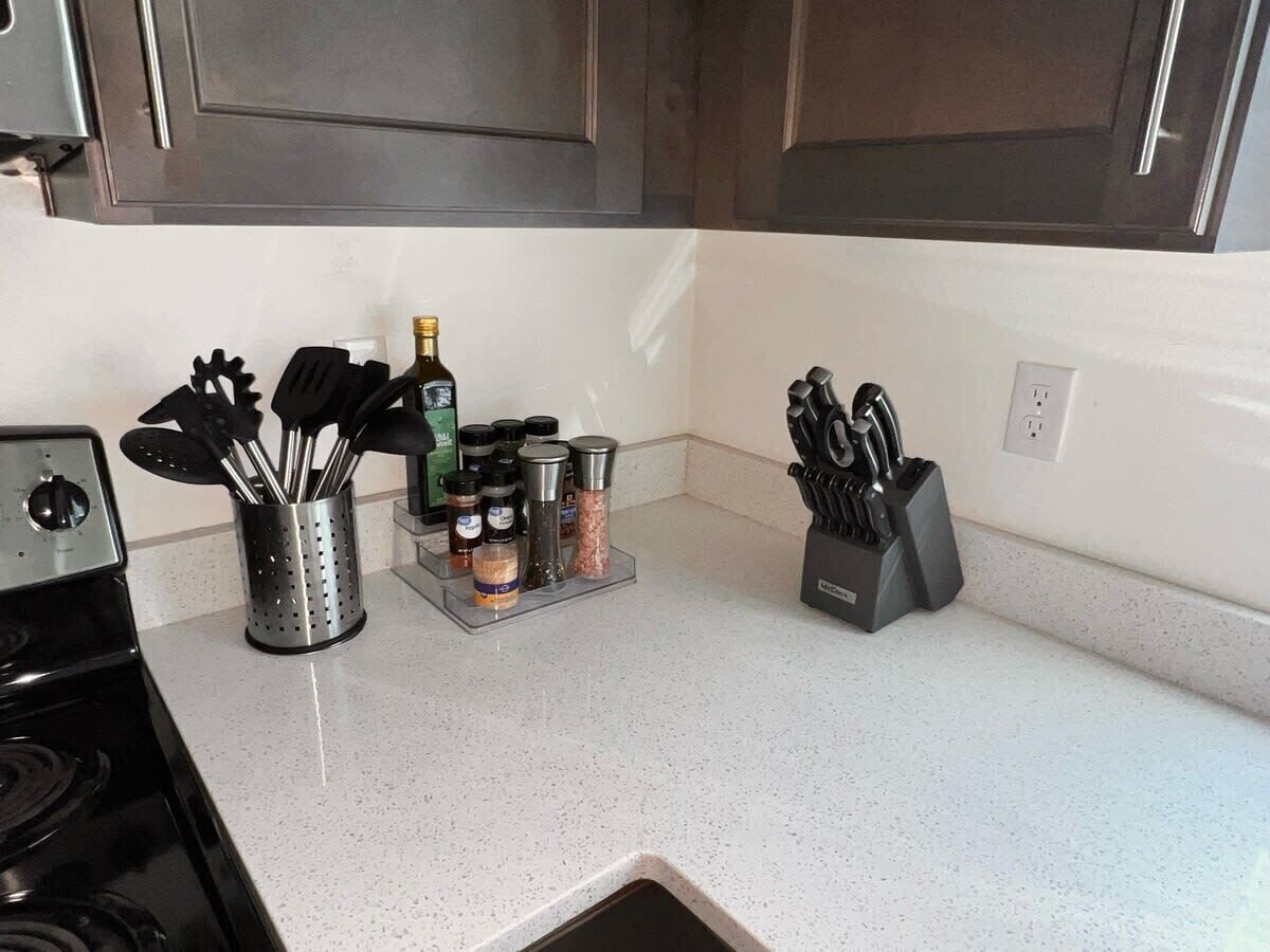 A kitchen with a stove, a spice rack, and a knife block.