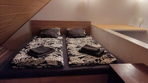 Ein kleines Zimmer mit einem Einzelbett, einem Holzkopfende und einer Holzbank am Fußende.