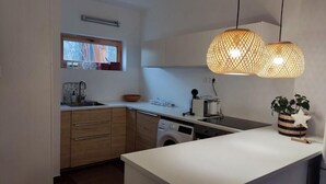 Eine moderne Küche mit integriertem Waschmaschine, einem Fenster mit Ausblick und zwei hängenden Pendelleuchten.