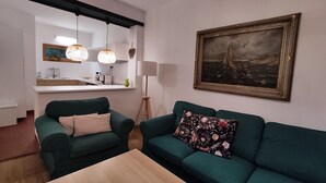Ein Wohnzimmer mit einem grünen Sofa, einem Holztisch und einem Bild an der Wand.
