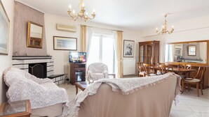 A spacious living room with a fireplace, a television, a dining area with a large mirror, and a piano. - Koridalos Terrace Apt w Spectacular View (Korydallos)