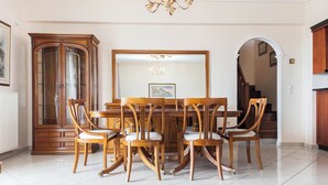 A dining area with a wooden table and chairs, a large mirror, and a chandelier. - Koridalos Terrace Apt w Spectacular View (Korydallos)