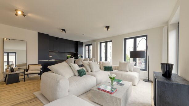 A modern living room with a large sectional sofa, a coffee table, and a dark wooden cabinet.