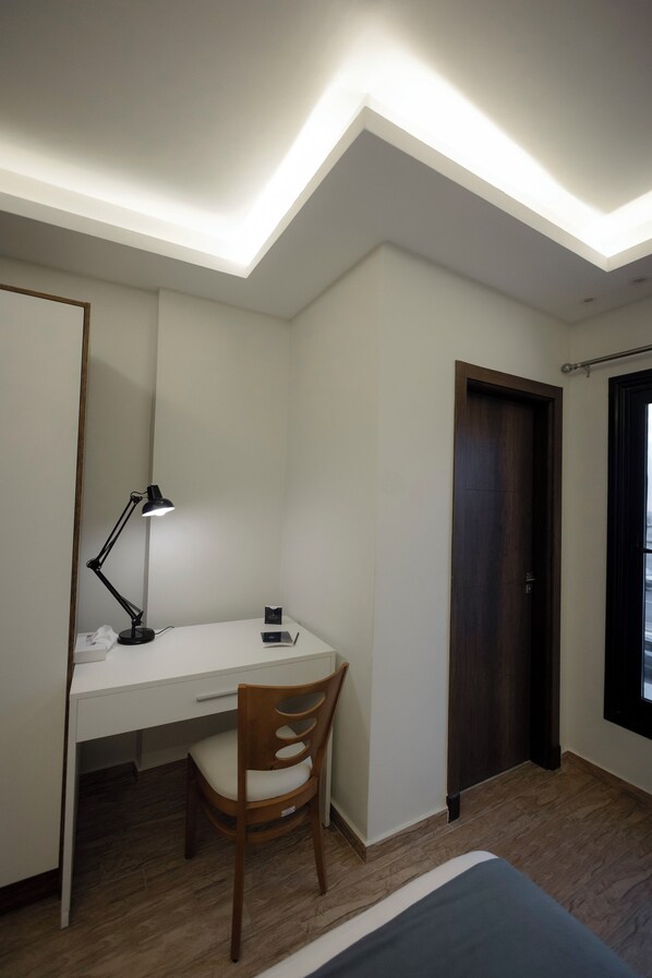A bedroom with a bed, a desk with a chair, a desk lamp, and a door. - Royal Inn Residence New Cairo (New Cairo)