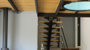 En moderne stue med sofa, dekorativ pude, pejs, stol og trappe.