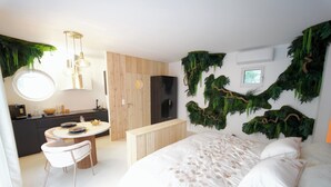 Un dormitorio moderno con una cama grande, una mesa de comedor redonda y una zona de cocina.