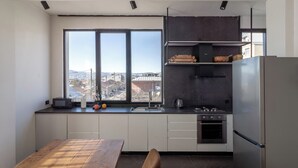 Een moderne keuken met een groot raam, een eettafel en een inbouwoven.
