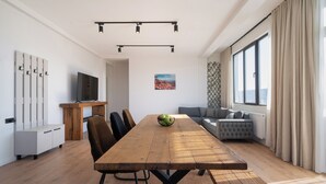 Een moderne woonkamer met een houten eettafel, stoelen, een bank en een televisie.