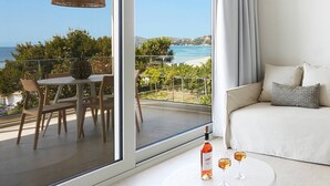A modern living room with a balcony, a dining area, and a sofa with cushions. - Skiathos Ammos Luxury Apartments in Megali Ammos Beach (Skiathos)