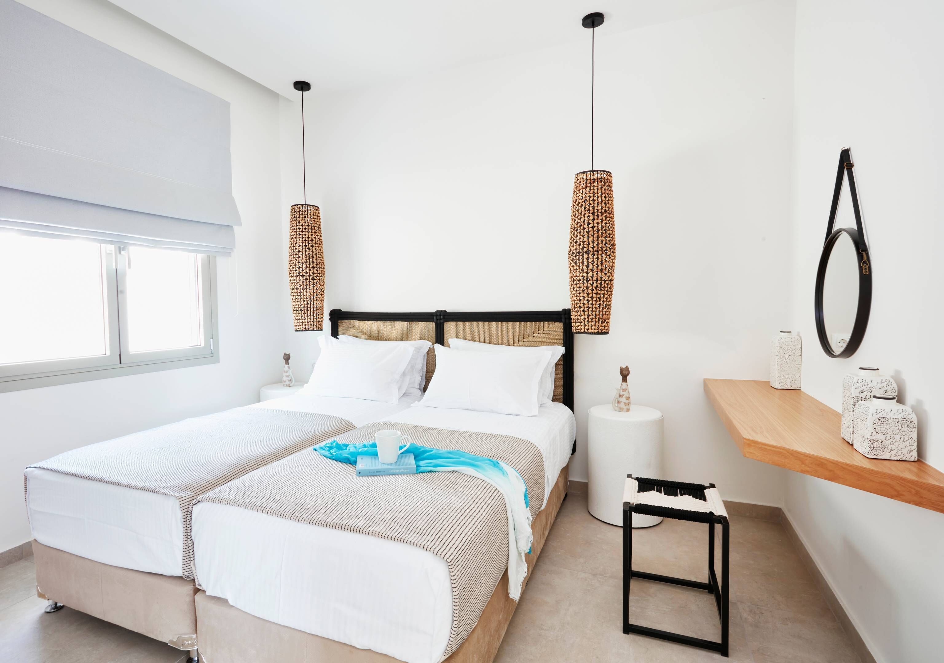 Un dormitorio moderno con una cama grande, mesitas de noche, una pequeña mesa y una lámpara colgante.