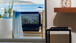 A balcony with a view of the sea, a hammock, a small table with a plant, and a shelf with decorative items. - Skiathos Ammos Luxury Apartments in Megali Ammos Beach (Skiathos)
