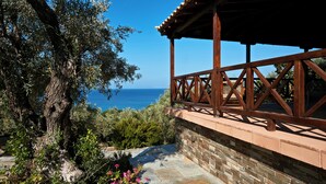 A wooden balcony with stone walls overlooking a clear blue sea. - Villa Ira Skiathos Luxury Villa (Skiathos)
