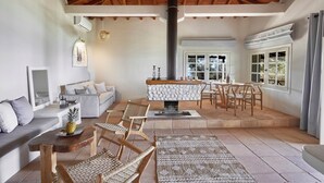A spacious living area with a high ceiling, a fireplace, and a dining table set for six. - Villa Ira Skiathos Luxury Villa (Skiathos)
