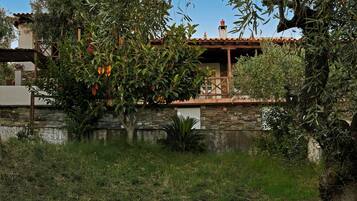 A stone building with a balcony overlooking a garden.