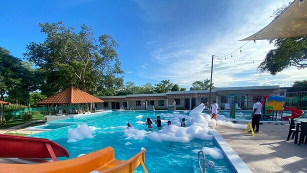 A swimming pool with inflatable structures, a slide, and a lifeguard stand. - Los Lirios Hotel  (El Coco)