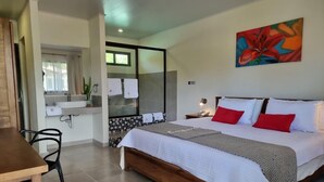 A bedroom with a bed, bedside table, and a painting. - Los Lirios Hotel  (El Coco)