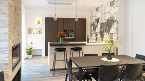 Une cuisine moderne avec des meubles de couleur sombre, un îlot central et des luminaires suspendus.