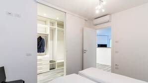 Une chambre d’hôtel moderne équipée d’un lit, d’une chaise, d’un dressing et d’un appareil de climatisation.