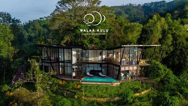 Une villa moderne à l’extérieur entièrement vitré, dotée d’une piscine et bordée d’une forêt luxuriante.