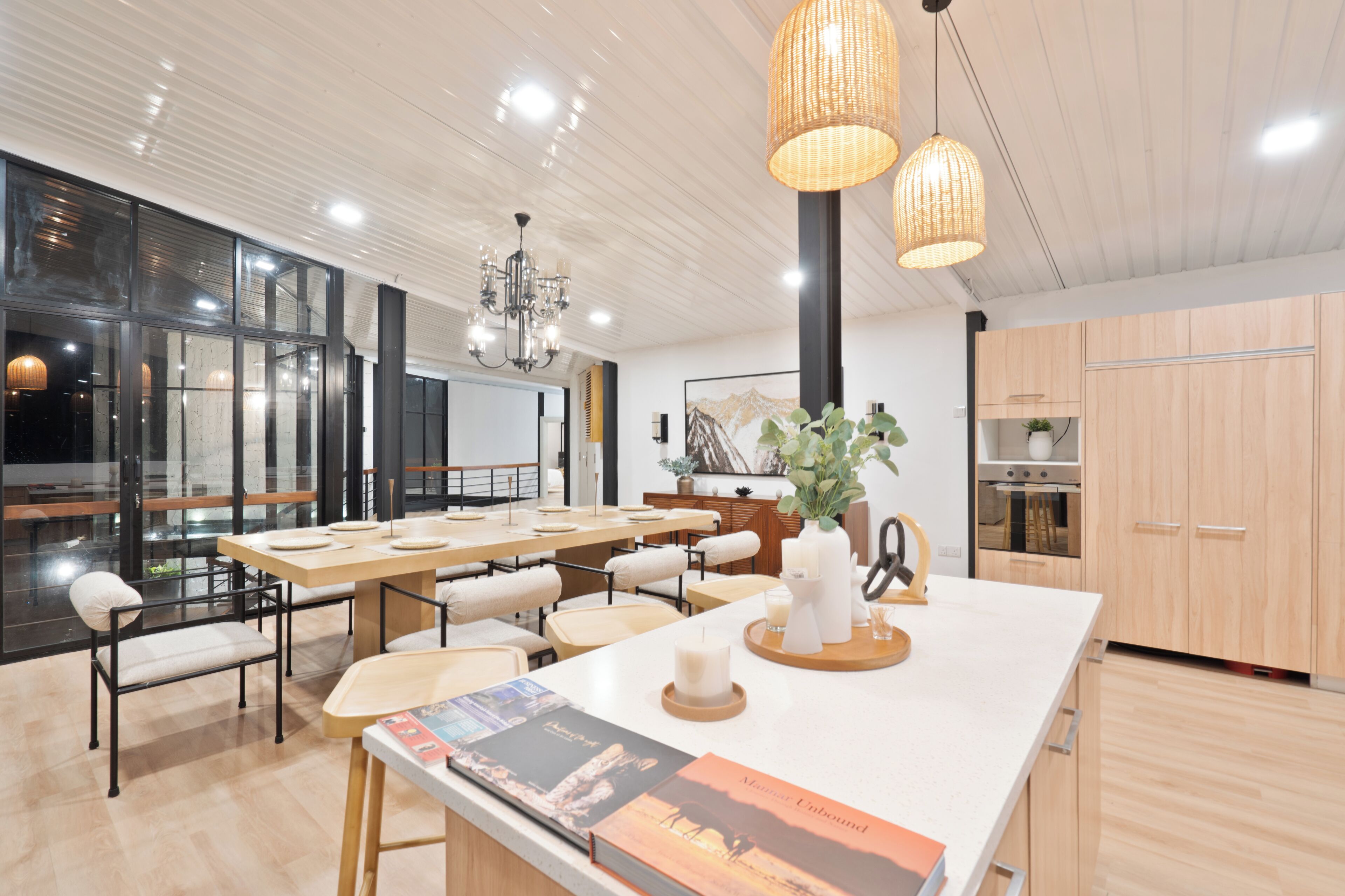 A modern kitchen with wooden cabinets, a large island with a white countertop, and pendant lighting.
