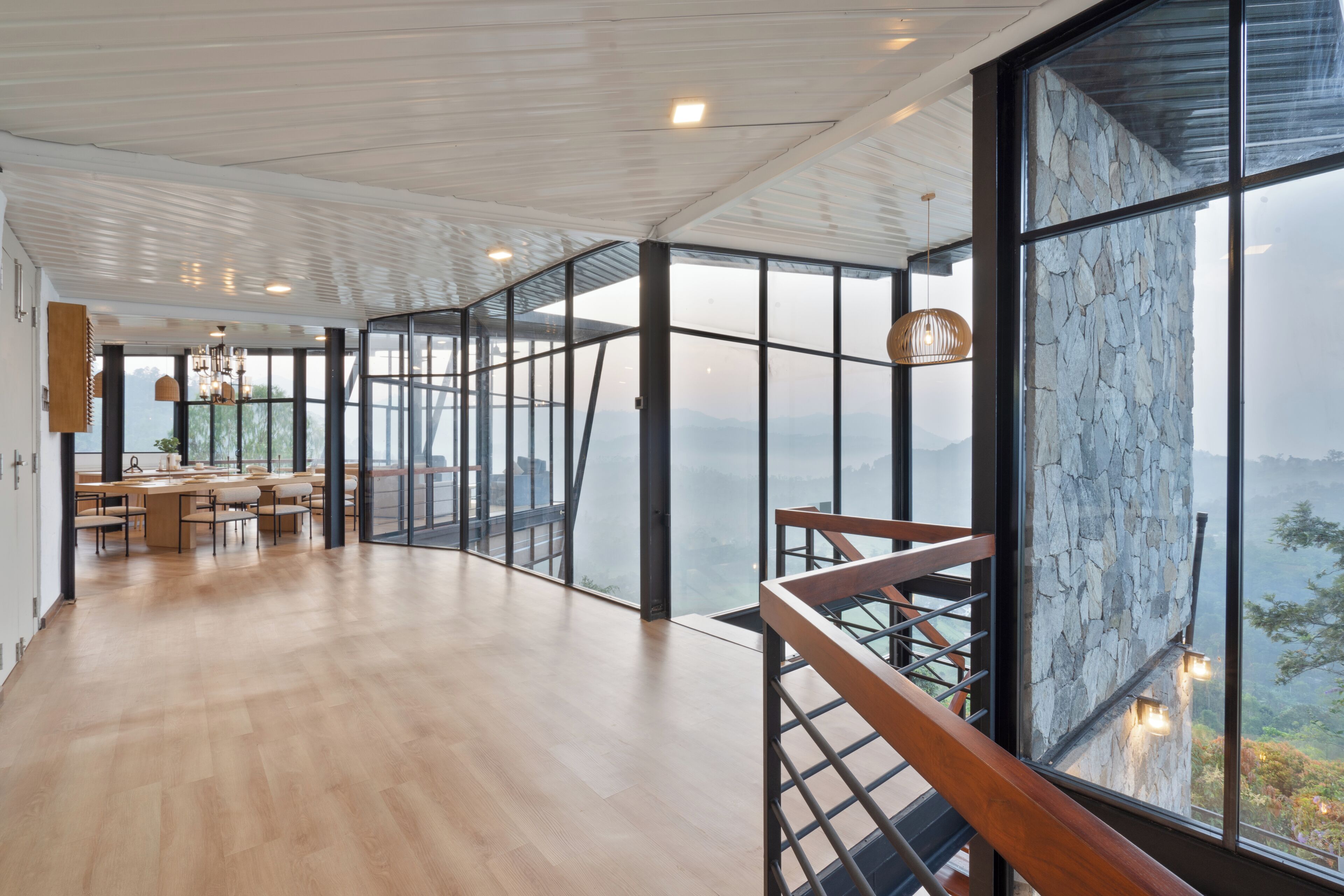 A spacious room with a wooden floor, large windows, and a view of a mountainous landscape.