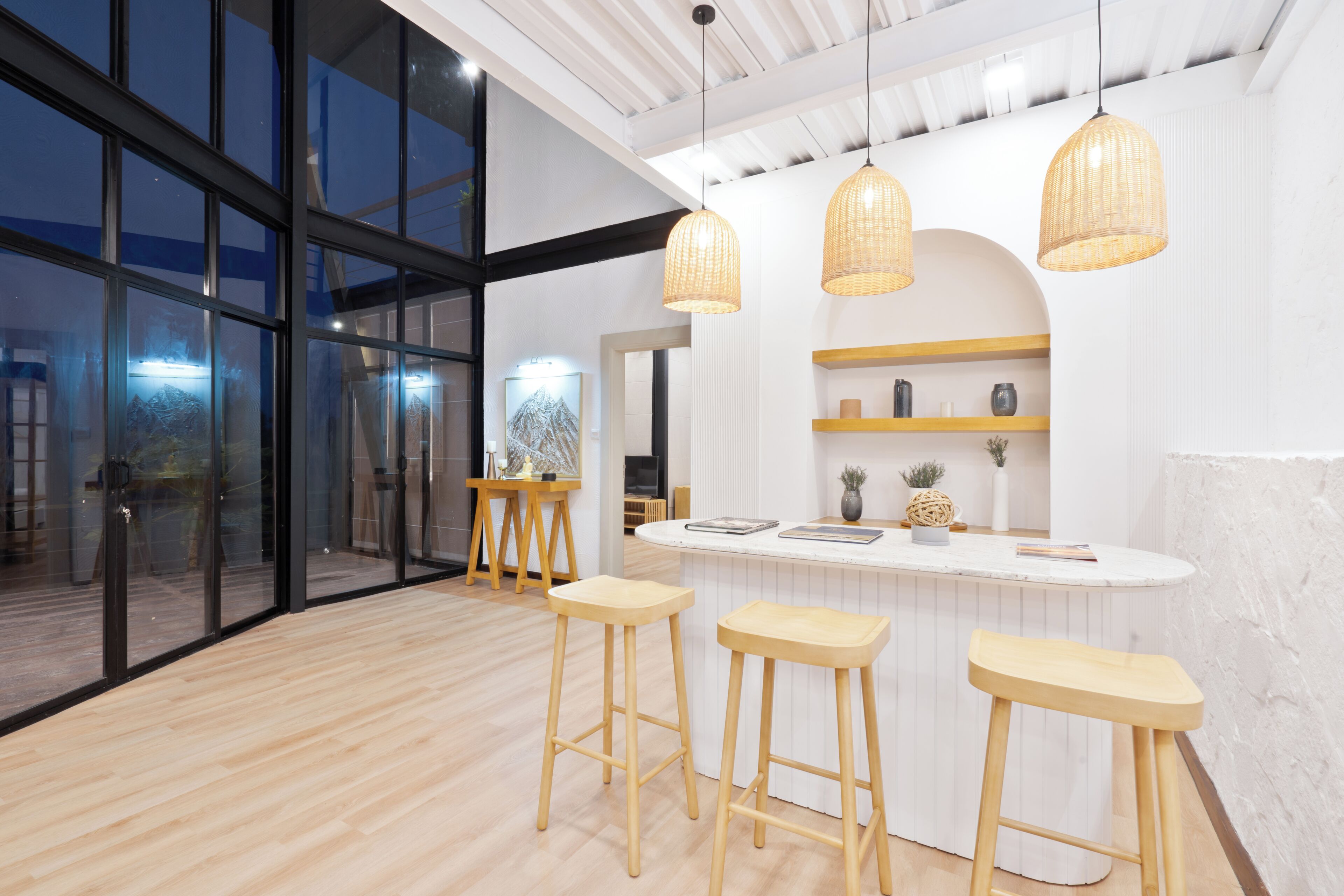 Un interior moderno con una zona de bar, taburetes de madera e iluminación colgante.