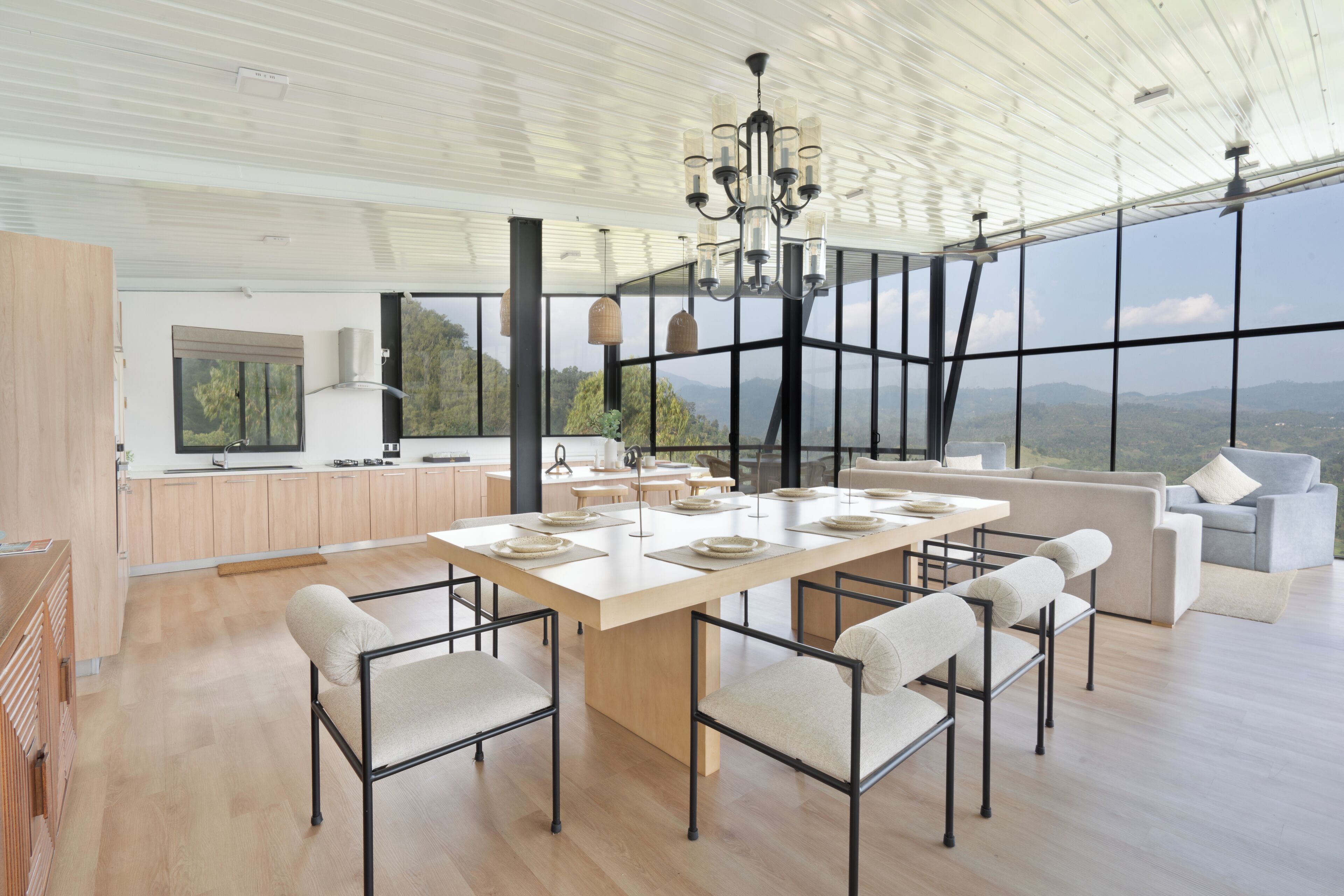 A spacious kitchen with a large island, modern furniture, and large windows offering a view of the mountains.